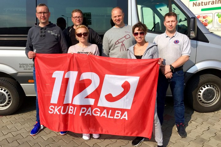 Nuotraukoje matomi greta mikroautobuso su numerio 112 vėliava stovintys žmonės
