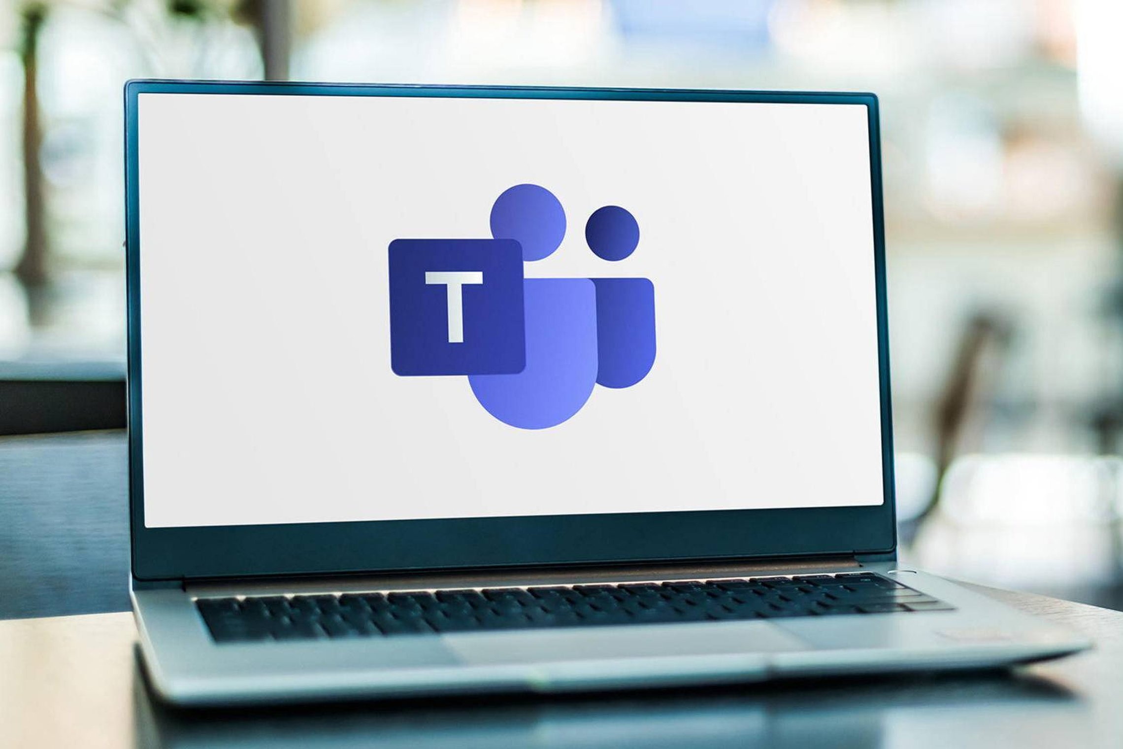 Nuotraukoje matomas nešiojamas kompiuteris su „Microsoft Teams“ logotipu ekrane