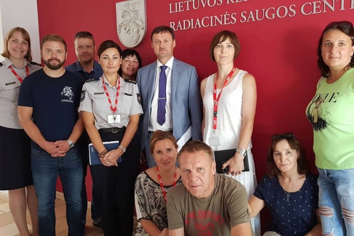 Nuotraukoje matomi Bendrojo pagalbos centro darbuotojai prie Radiacinės saugos centro sienelės