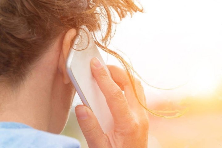 Nuotraukoje iš nugaros matoma mobiliuoju telefonu skambinanti moteris