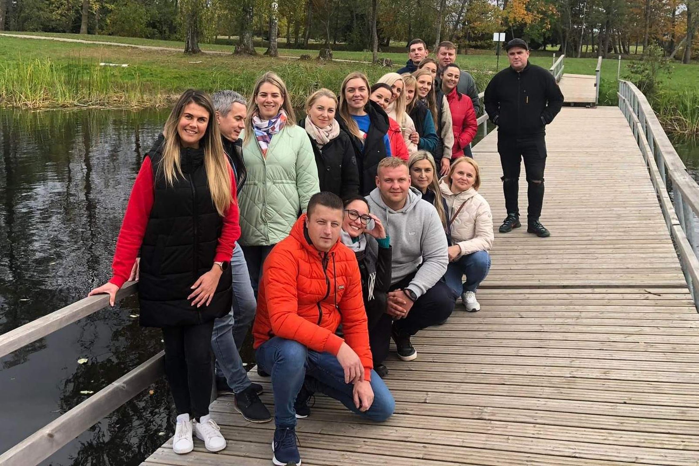 Nuotraukoje matoma grupė besišypsančių žmonių ant tilto