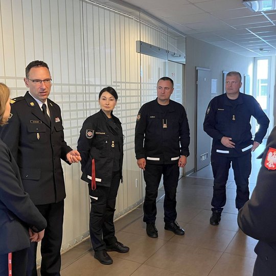 Nuotraukoje matomi keli svečiai ir juos lydintys asmenys koridoriuje