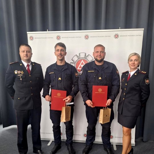 Nuotraukoje matomi prie sienelės įsiamžinę keturi pareigūnai - Pajėgų valdymo skyriaus vadovybė ir du apdovanoti darbuotojai.