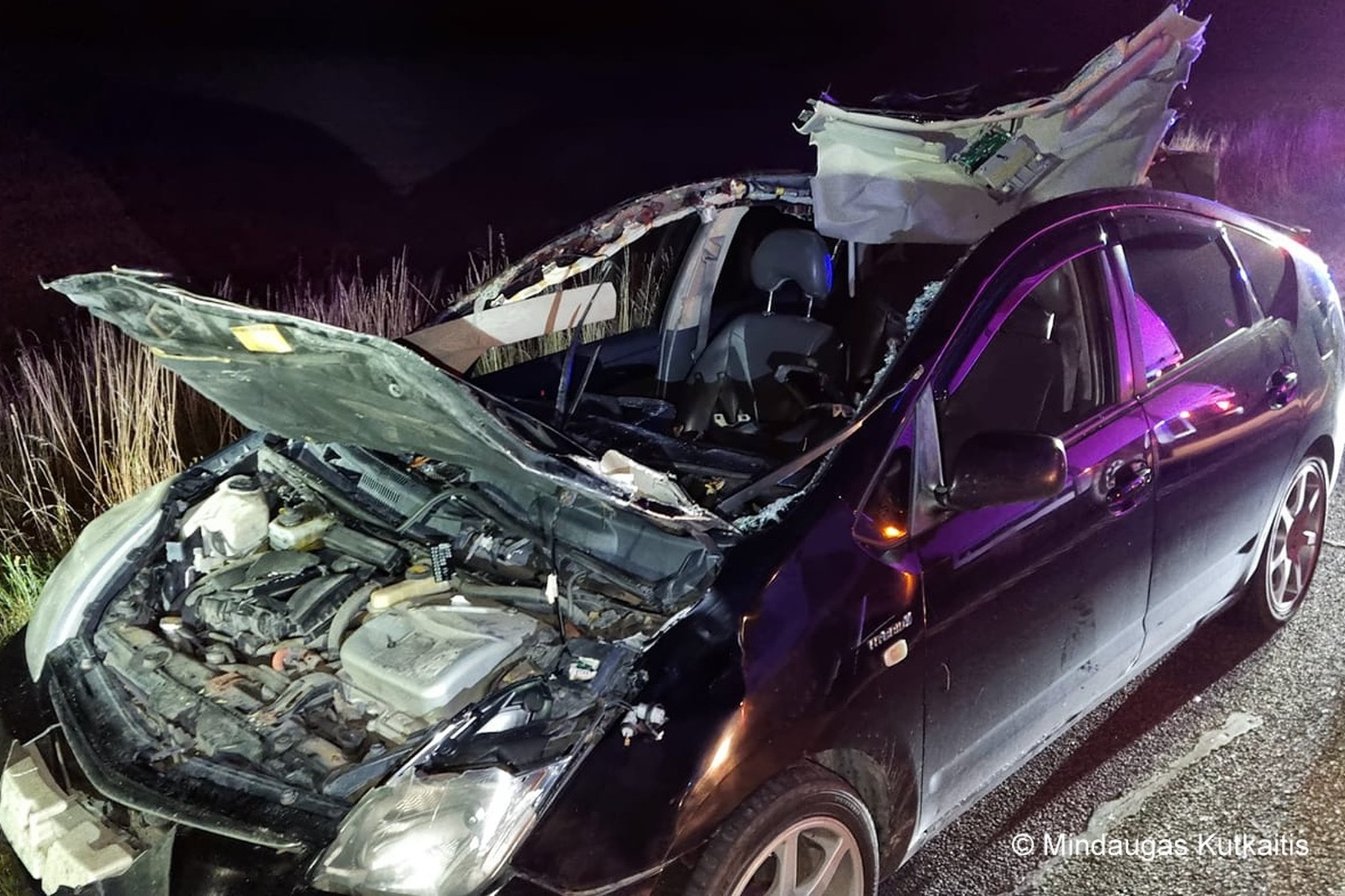 Nuotraukoje matomas naktį po eismo įvykio sudaužytas automobilis