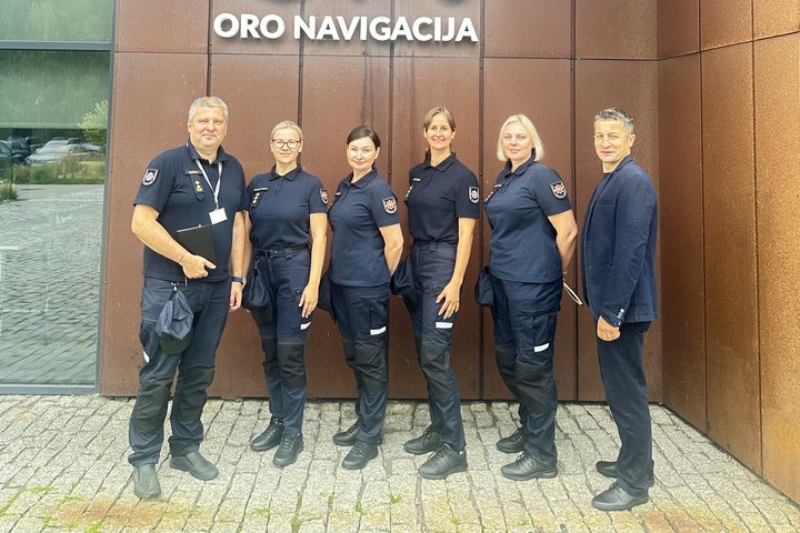 Nuotraukoje matomi  penki Bendrojo pagalbos centro pareigūnai ir „Oro navigacijos“ atstovas, stovintys prie pastato sienos lauke
