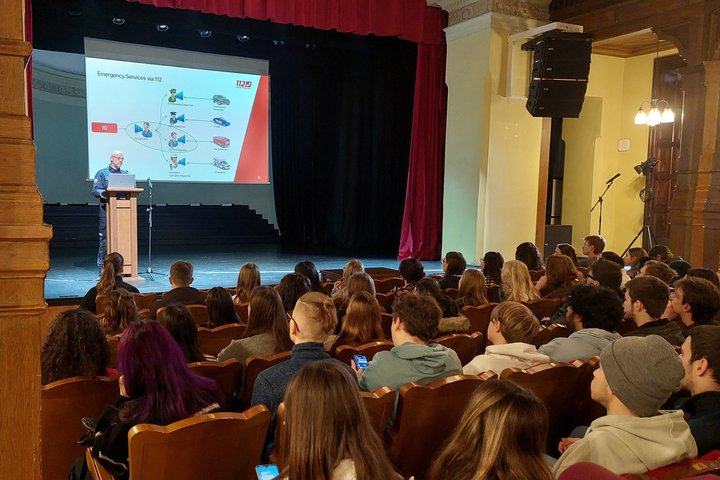 Nuotraukoje matoma salė Vilniaus universitete ir ant scenos stovintis pranešėjas